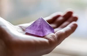Mano che trasporta una piramide di ametista